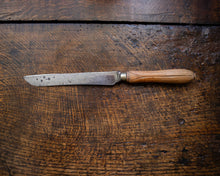 Old bread knife with a wooden handle on a rustic wooden surface