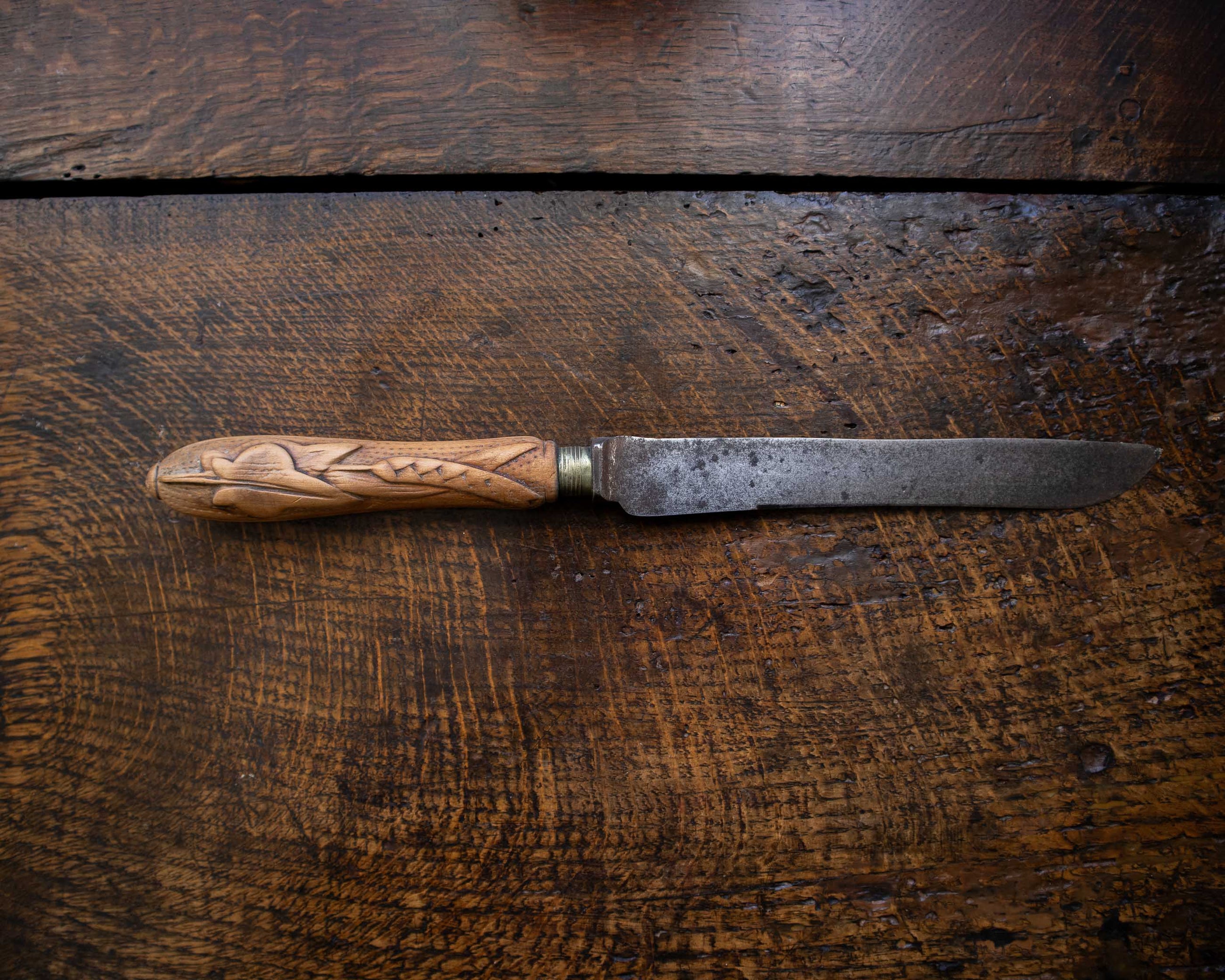 Antique knife with a wooden handle on a dark wooden surface
