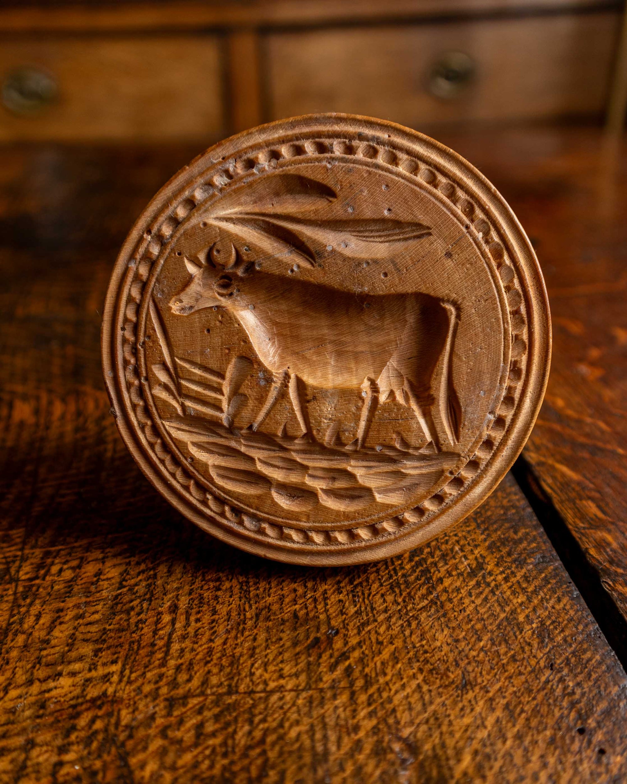 Wooden butter stamp with a cow design on a wooden surface