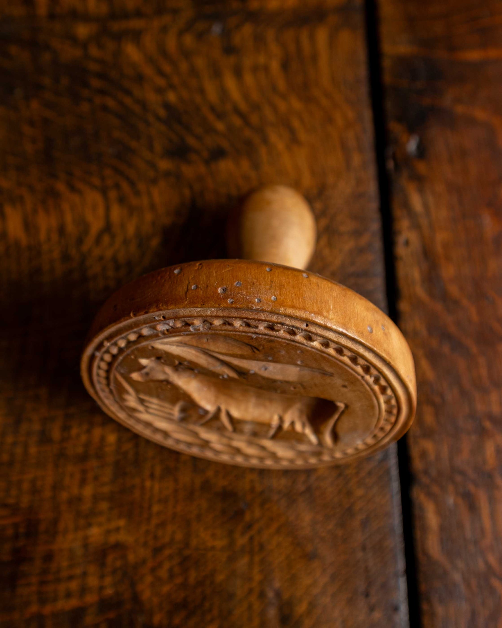 Wooden butter stamp with a carved design on a wooden surface