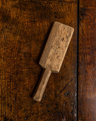 Wooden butter paddle with grooves on a wooden surface