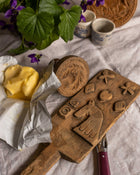 Wooden butter stamps on a tablecloth with butter and flowers.