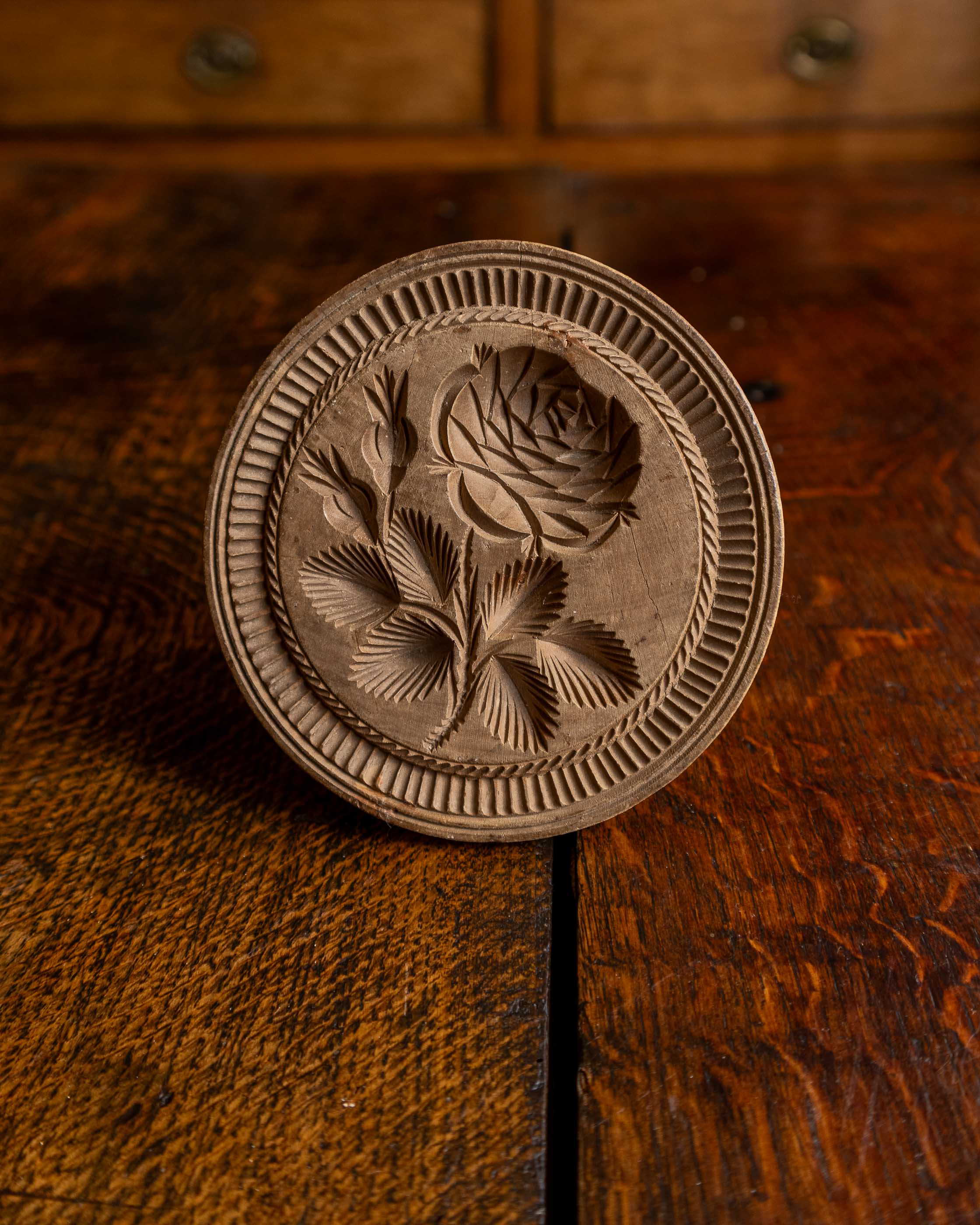 Wooden butter stamp with floral carving on a wooden surface