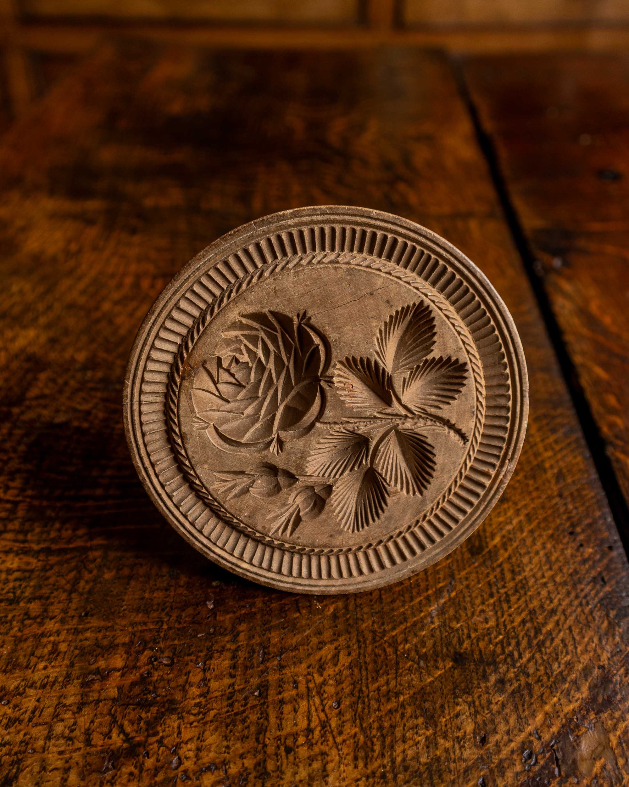 Wooden butter stamp with floral design on a wooden surface