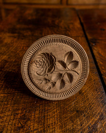 Wooden butter stamp with floral design on a wooden surface