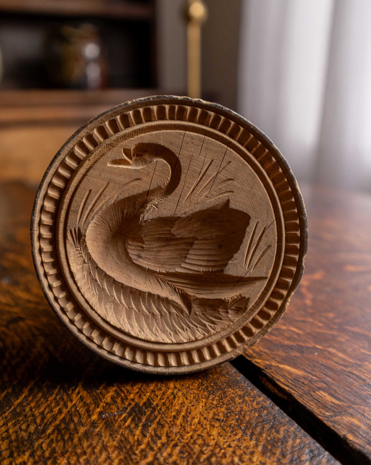 Wooden butter stamp with a swan design on a wooden surface