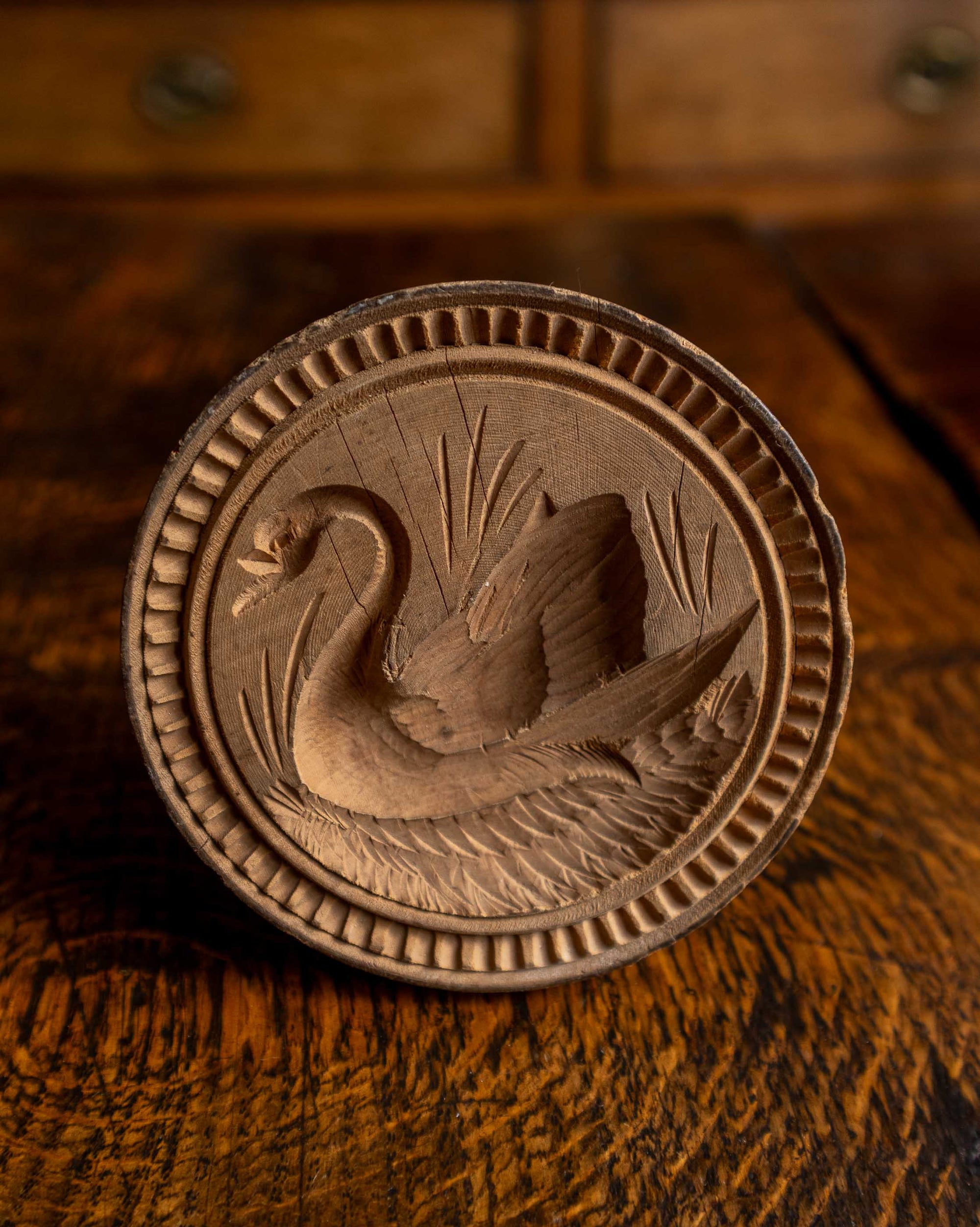 Wooden butter stamp with a swan design on a wooden surface