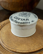 Vintage-style caviar container with a decorative lid on a wooden surface