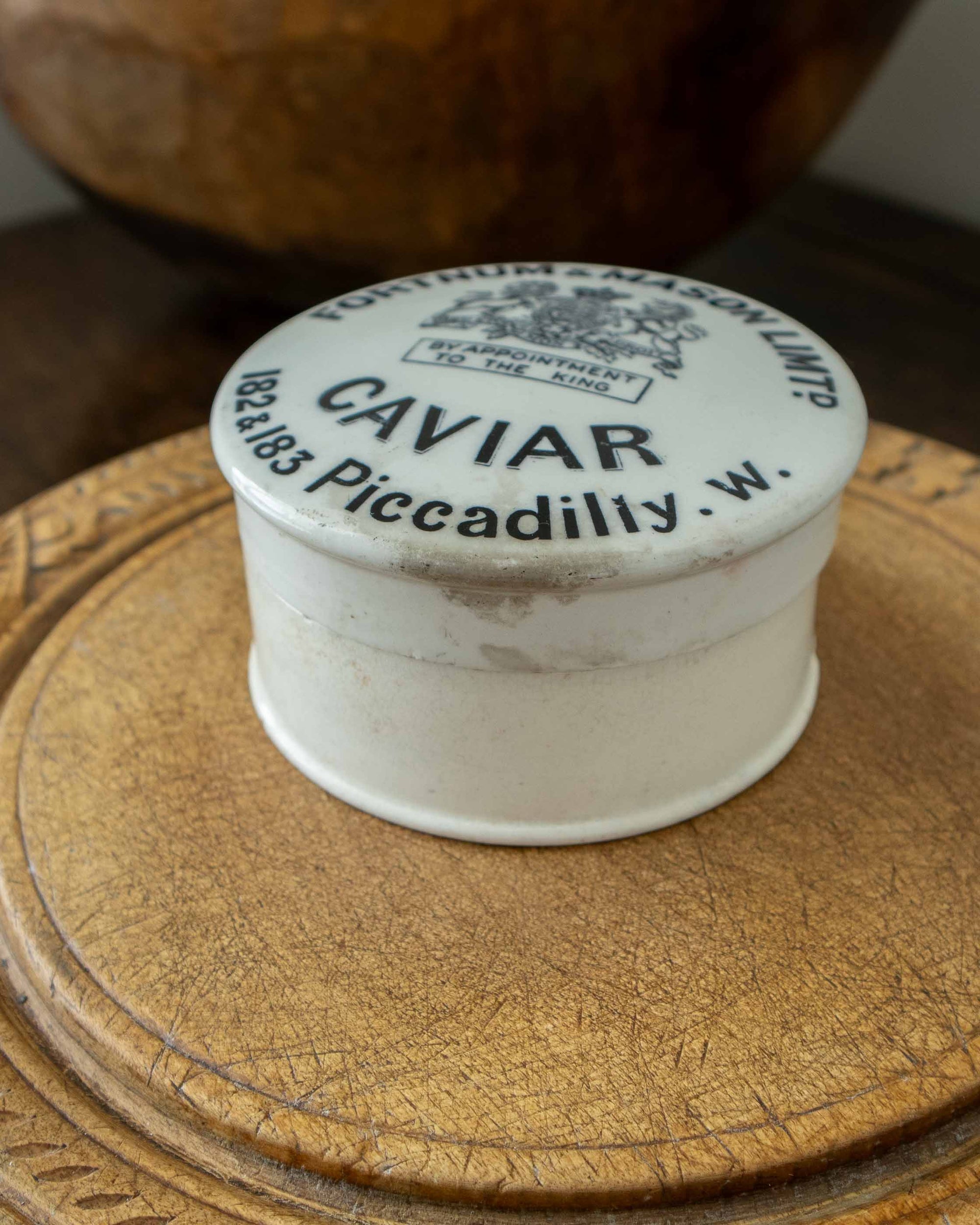 Vintage-style caviar container with a decorative lid on a wooden surface