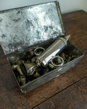 Collection of icing nozzles in a vintage metal box on a wooden surface