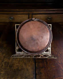 Copper dish on a metal stand with a wooden background