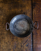 Vintage copper dish with handles on a wooden surface