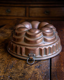 Copper bundt cake mould on a wooden surface