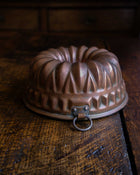 Copper bundt cake mould on a wooden surface