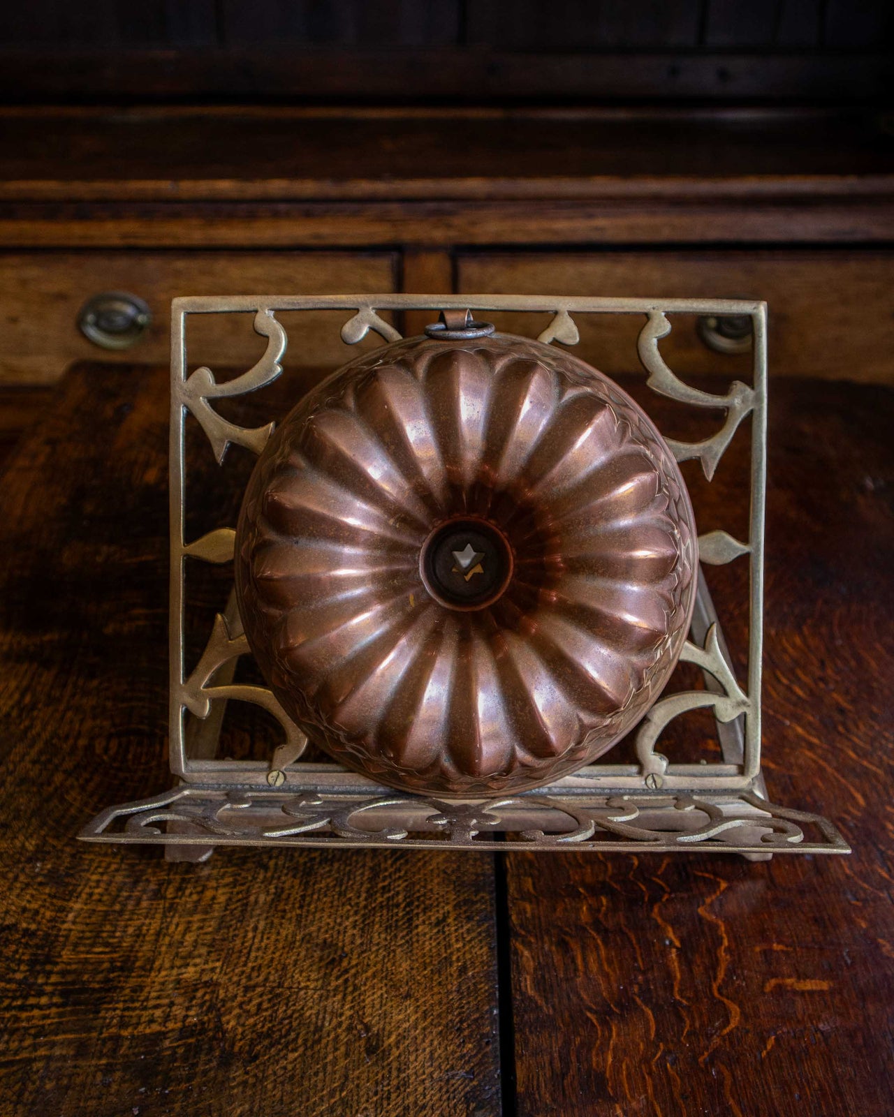 Copper bundt cake mould on a decorative metal stand against a wooden background