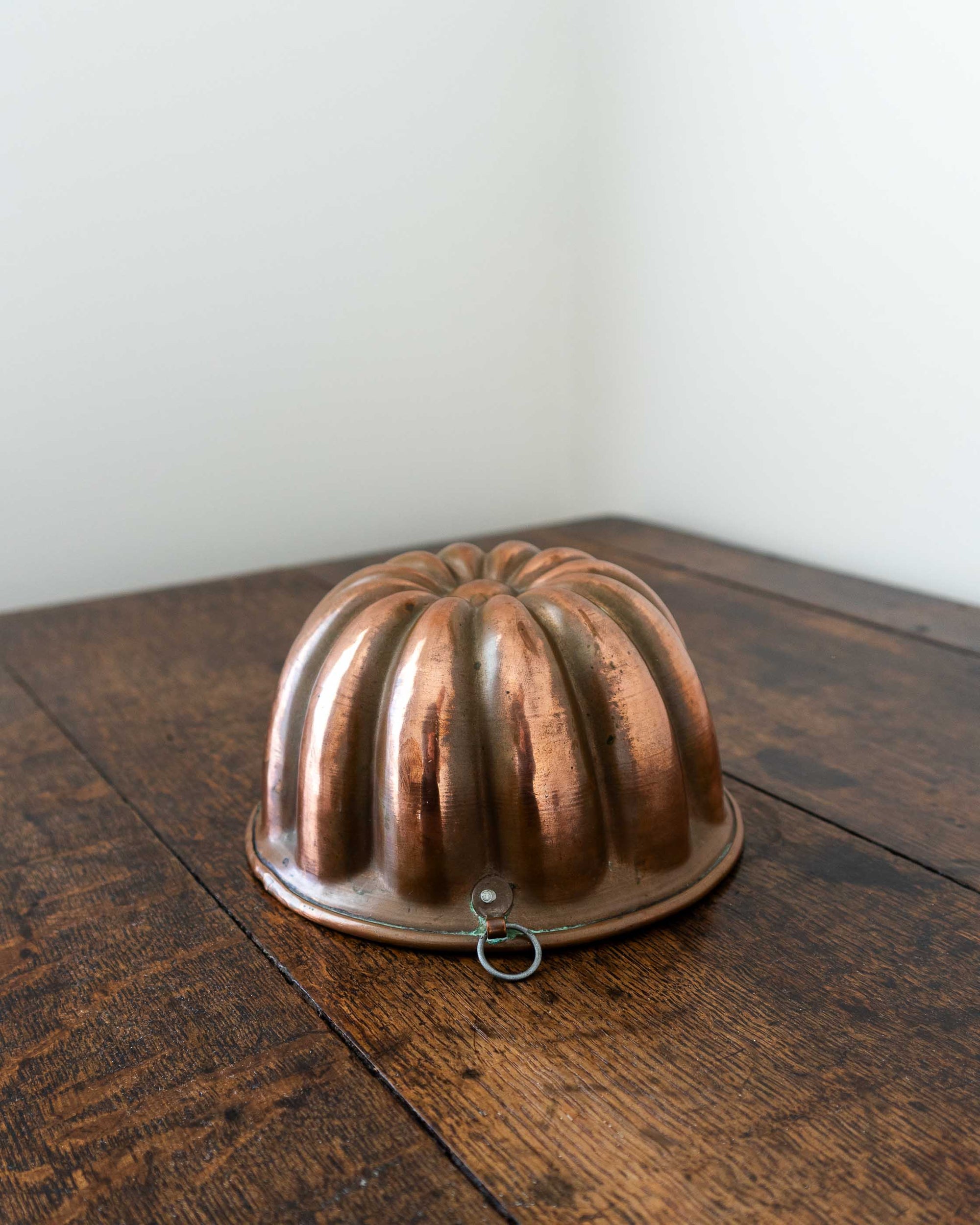 Copper jelly mould on a wooden surface with a white background