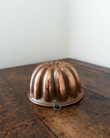 Copper jelly mould on a wooden surface with a white background