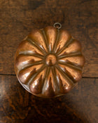 Copper jelly mould on a wooden surface with a white background