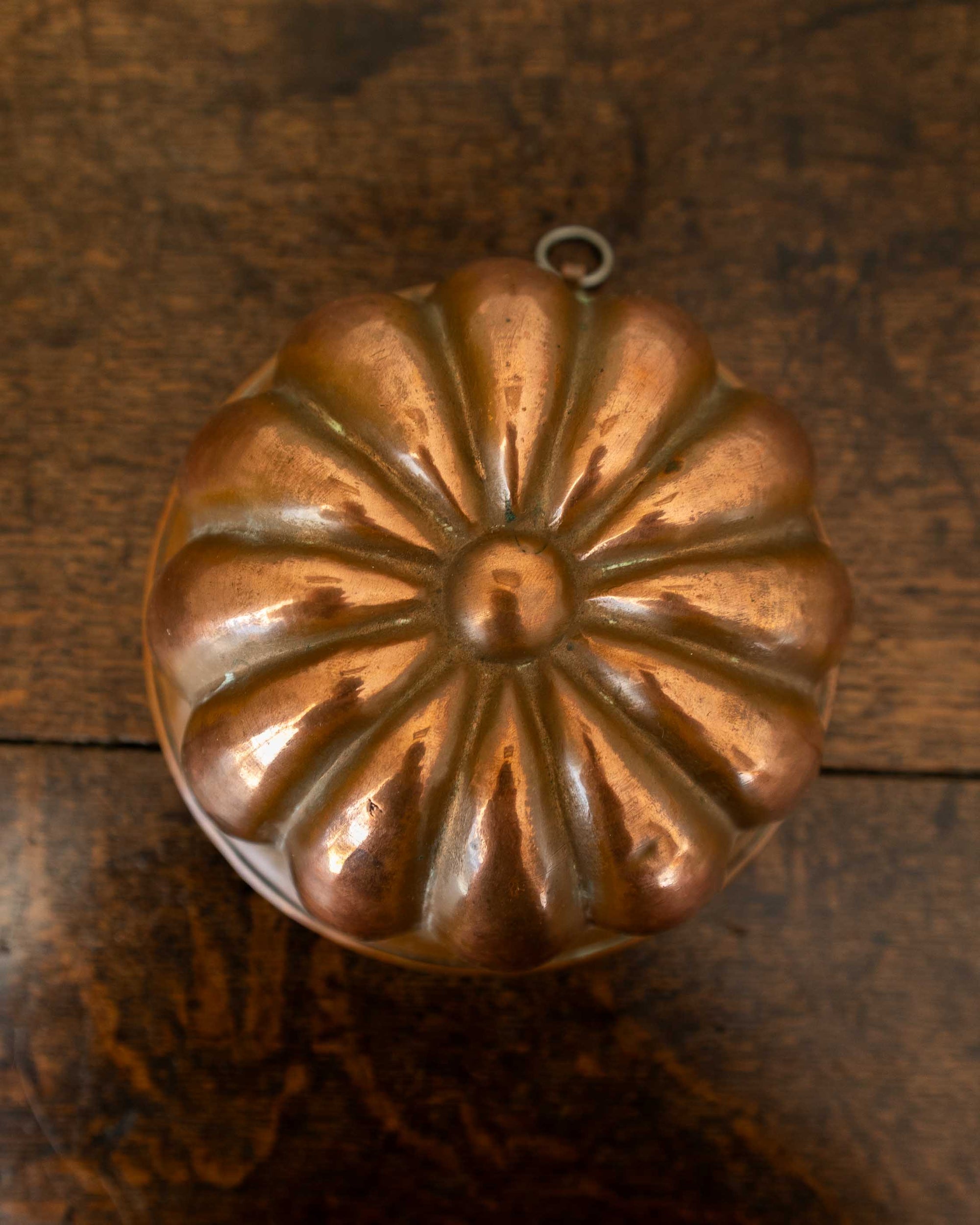 Copper jelly mould on a wooden surface with a white background