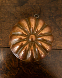 Copper jelly mould on a wooden surface with a white background