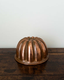 Copper jelly mould on a wooden surface with a white background