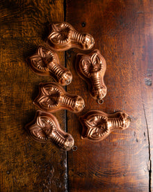 Set of six copper lobster moulds on a wooden surface