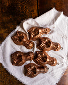 Set of copper mould shapes on a white cloth with a wooden background