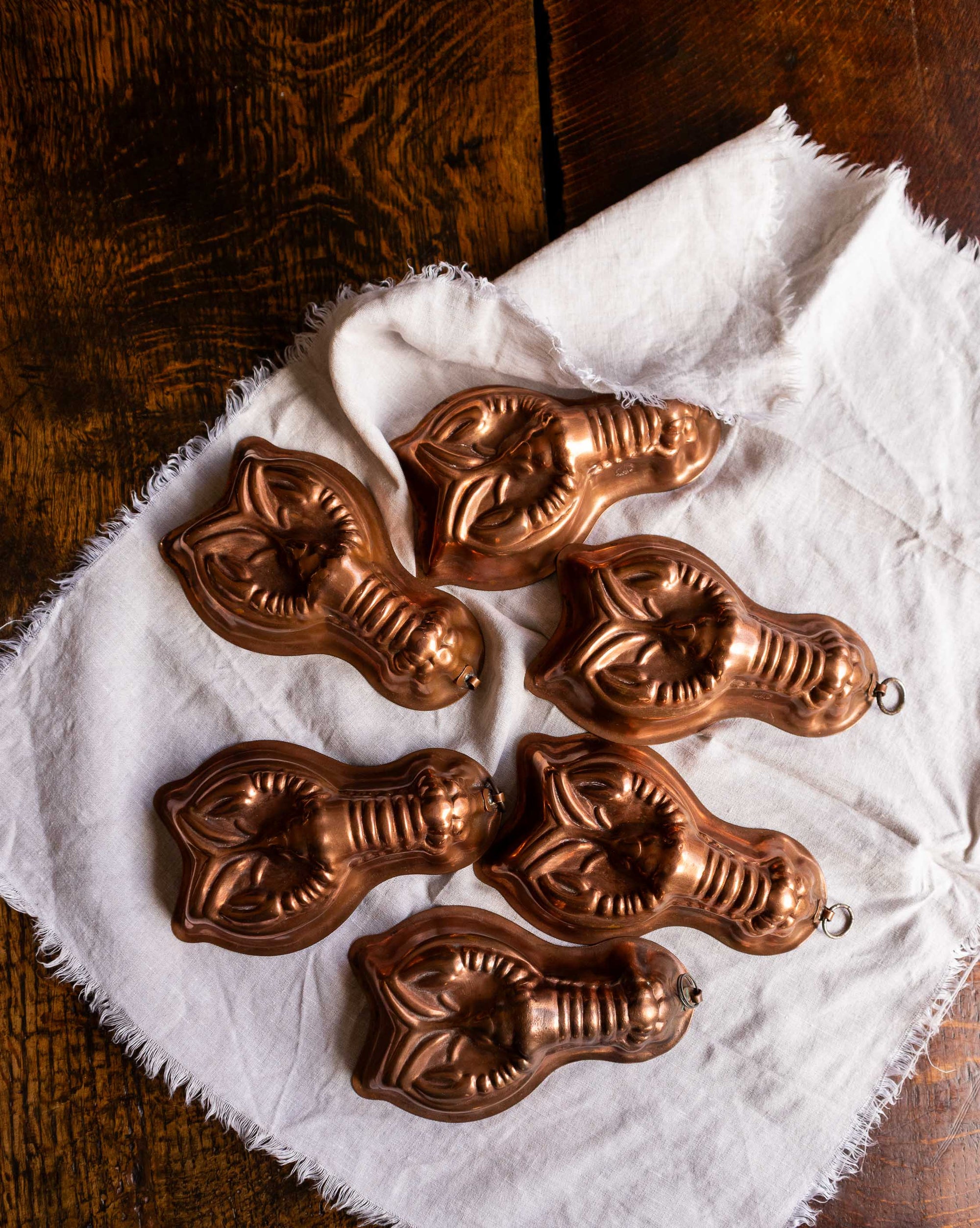 Set of copper mould shapes on a white cloth with a wooden background