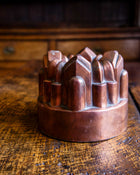 Copper jelly mould with geometric shapes on a rustic wooden surface