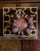 Decorative metal trivet with a copper-jelly mould on a wooden surface