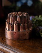 Copper mould with intricate design on a wooden surface