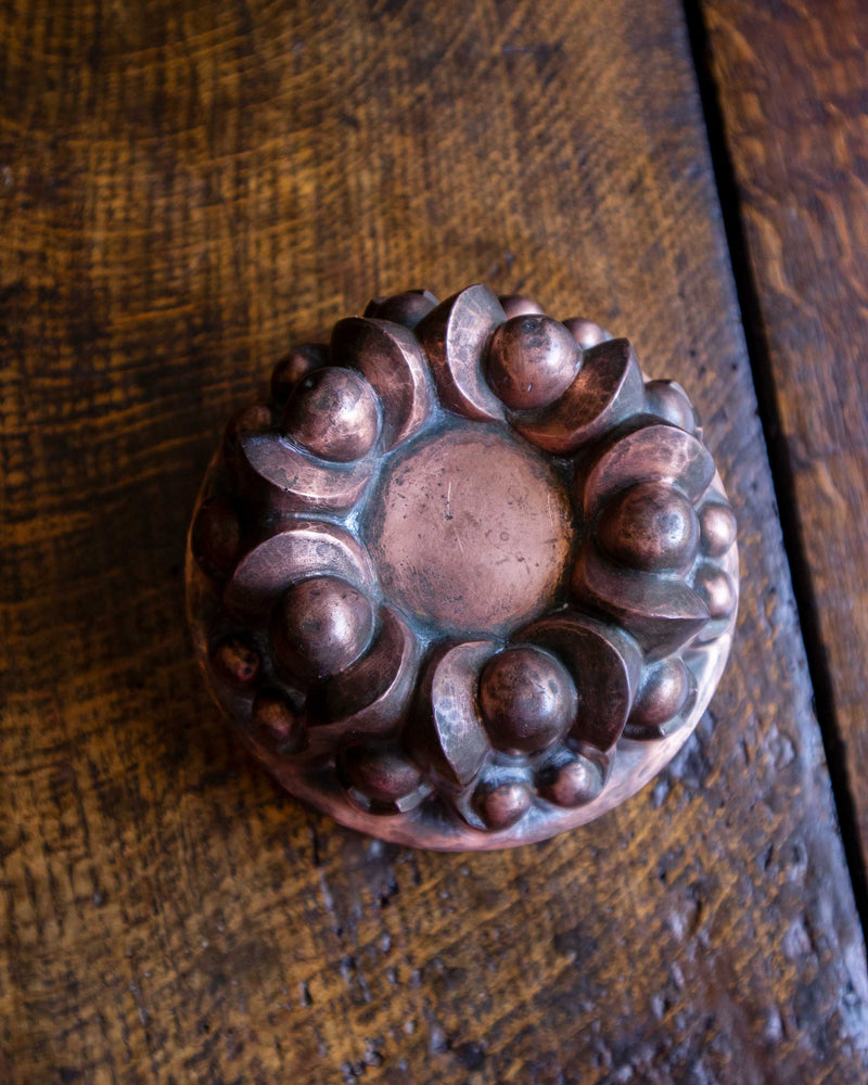 Decorative copper jelly mould on a wooden surface