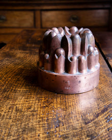 Decorative copper jelly mould on a wooden surface