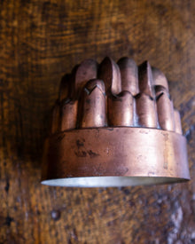Copper jelly mould with intricate design on a wooden surface