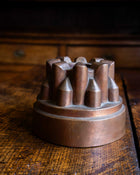 Copper jelly mould with pointed shapes on a wooden surface