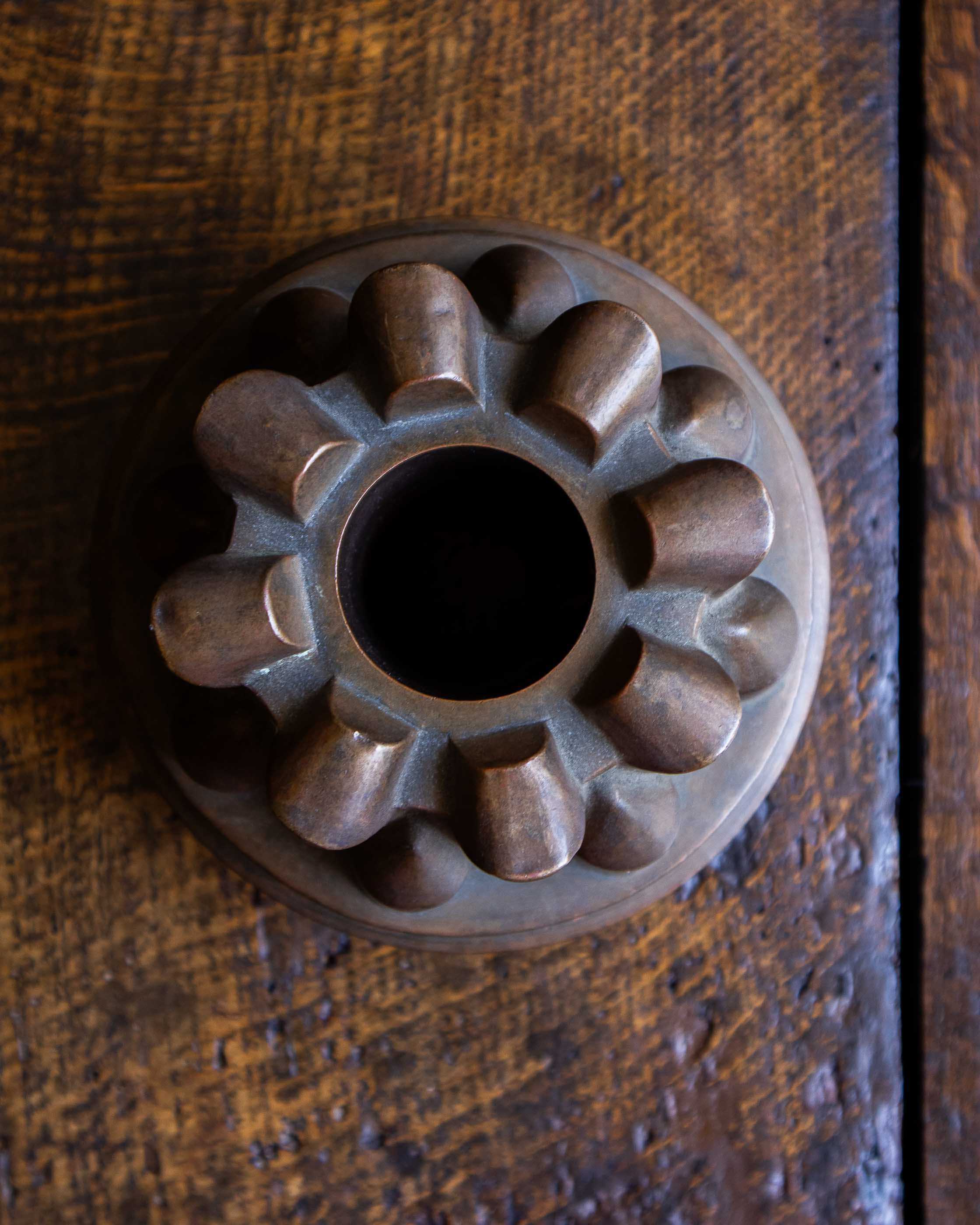 Copper jelly mould with pointed shapes on a wooden surface
