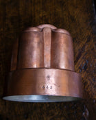 Copper jelly mould with '443' marking on a wooden surface