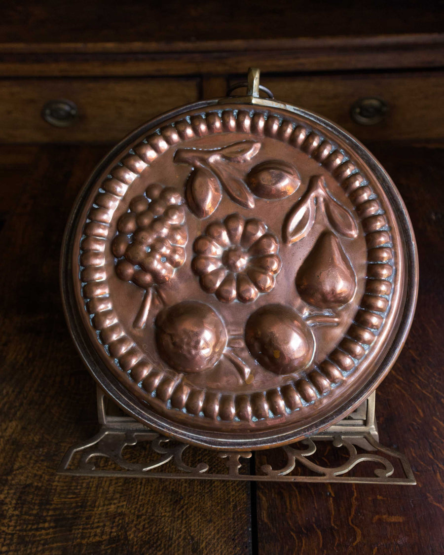 Copper mould with fruit design on a wooden surface