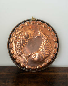 Copper mould with a fish design on a wooden surface and light white background