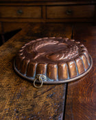 Copper mould with engraved design on a wooden surface