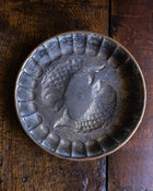 Decorative copper mould with fish design on a wooden surface