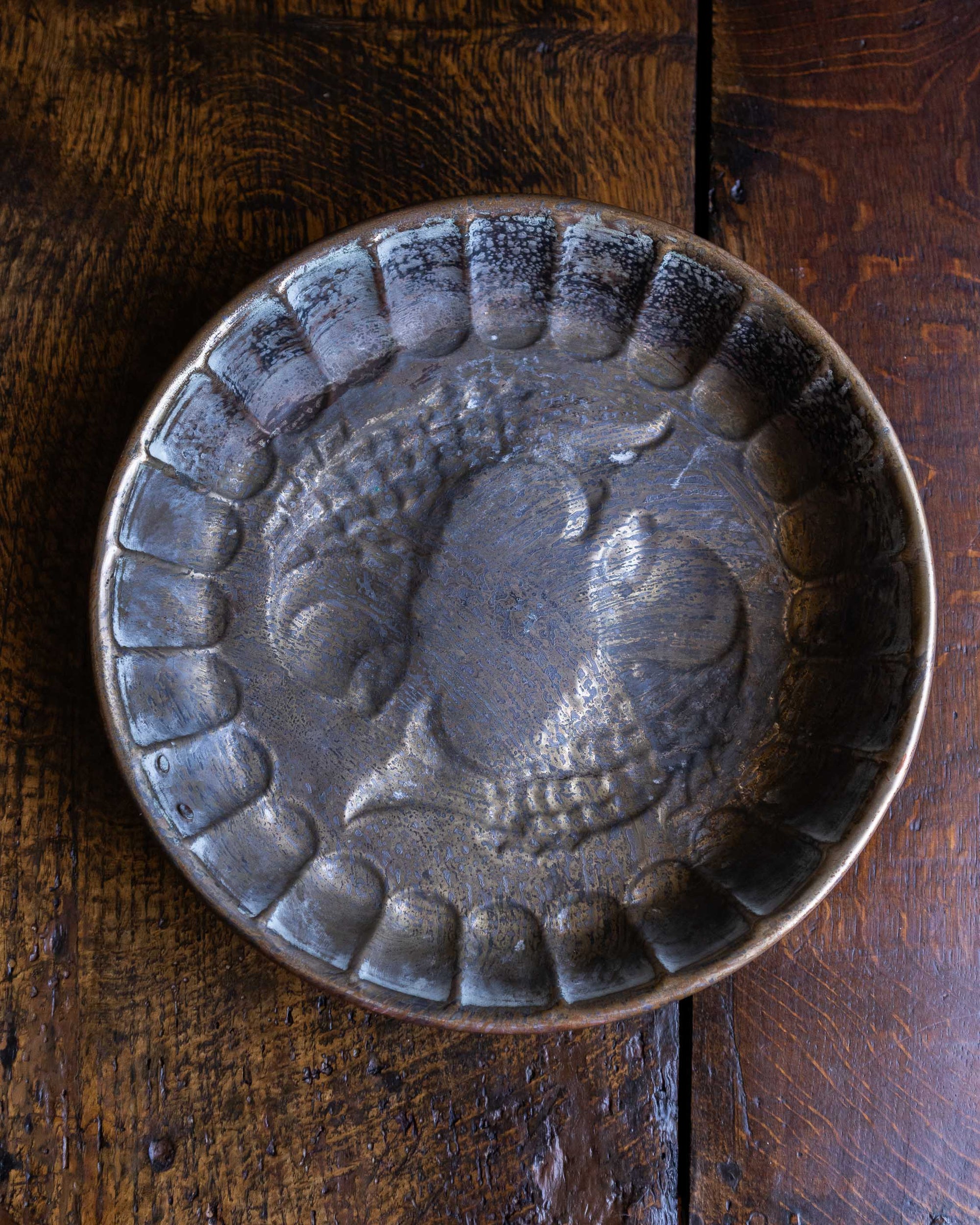 Decorative copper mould with fish design on a wooden surface