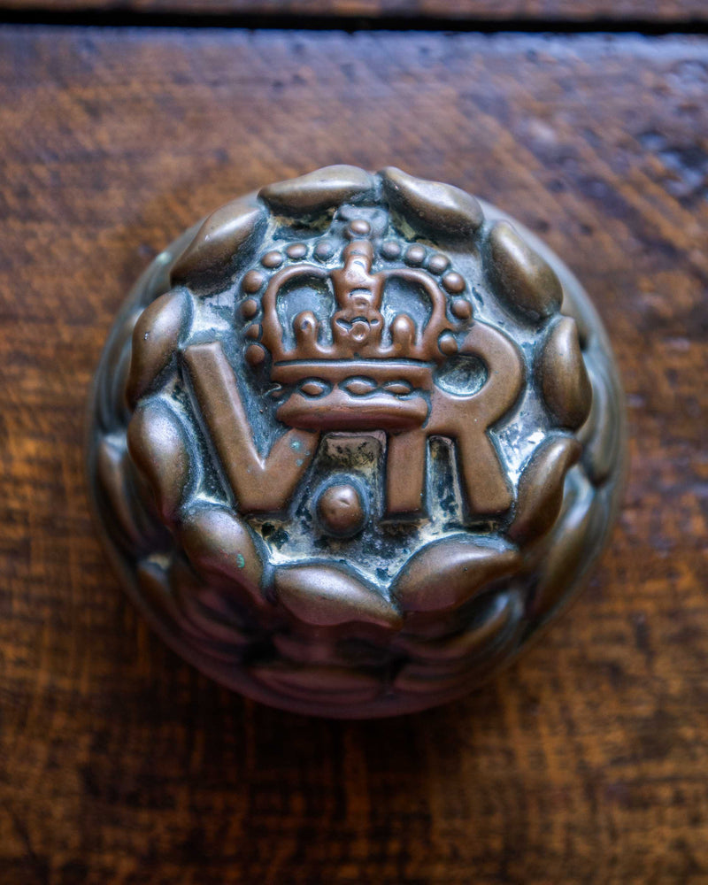 Copper jelly mould with VR cipher on a wooden surface. 