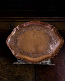 Decorative copper tray on a stand with a dark background