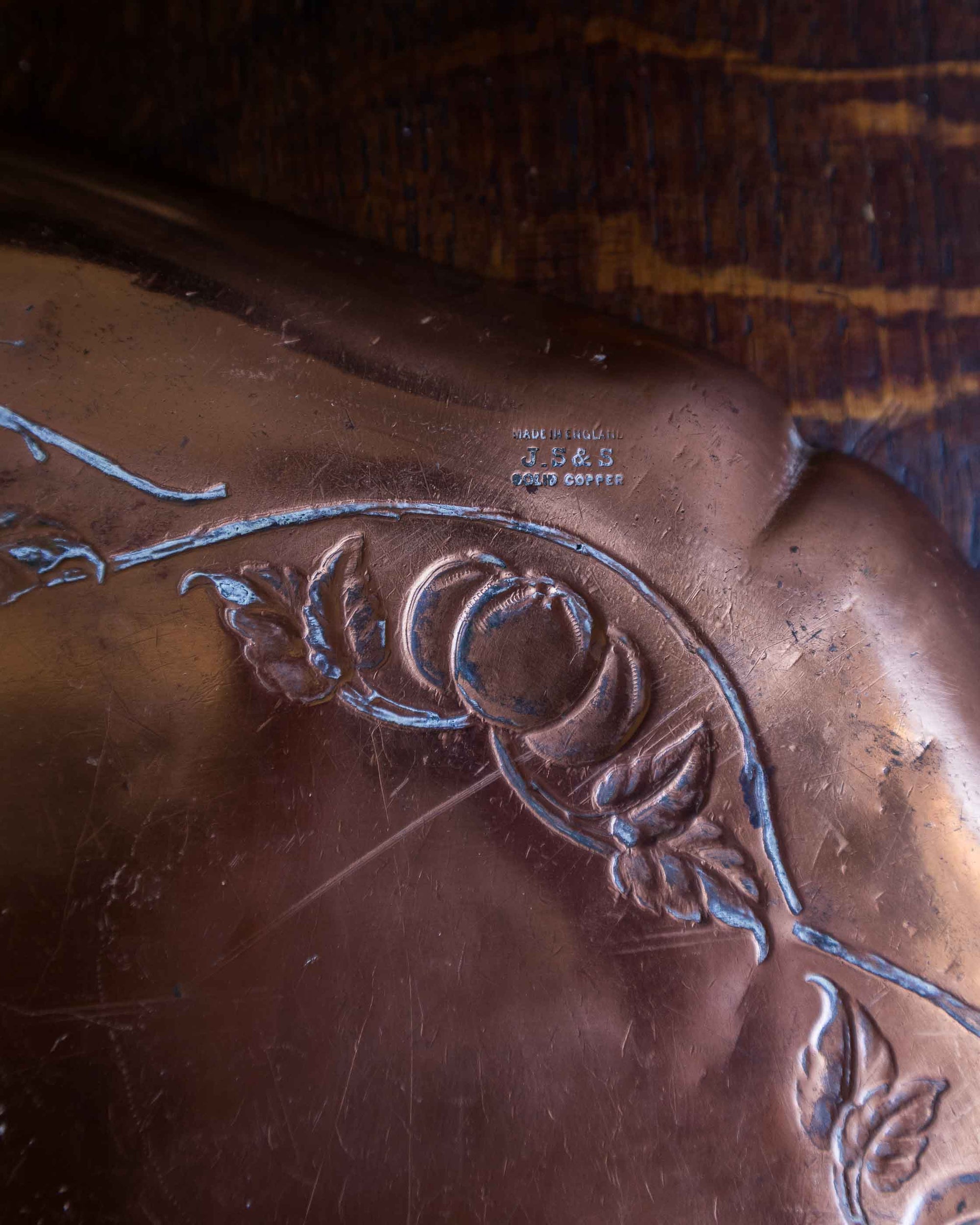 Close-up of a copper tray with engraved design and visible brand name.