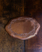 Decorative copper tray with engraved design on a wooden surface