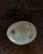 White ceramic mould with decorative feet on a wooden surface