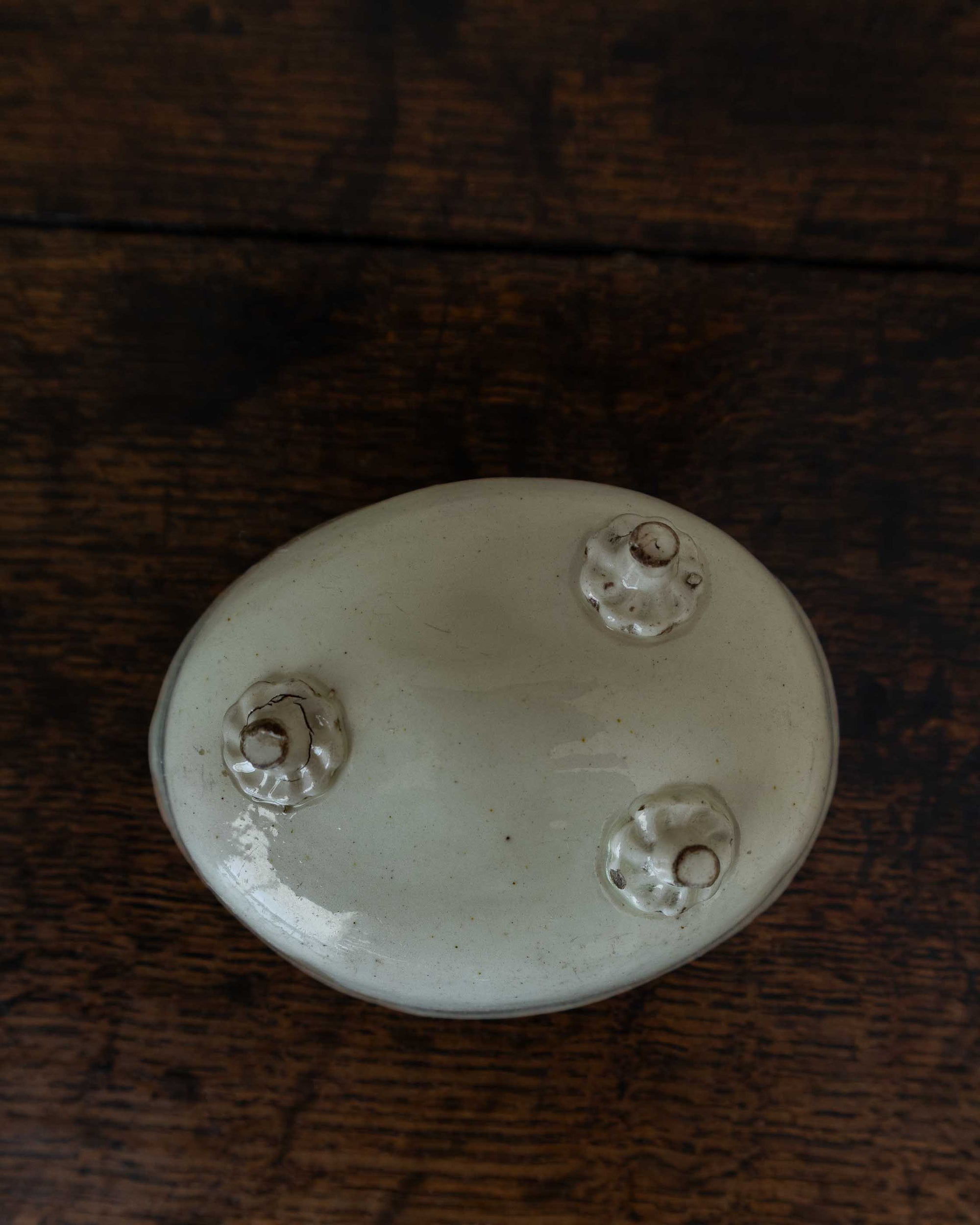 White ceramic mould with decorative feet on a wooden surface