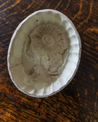 Decorative ceramic mould with floral design on a wooden surface