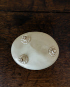 White ceramic mould with four small feet on a wooden surface